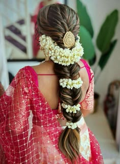 a woman with long hair and flowers in her hair, wearing a red sari