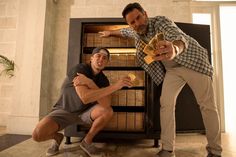 two men standing next to each other in front of a book case