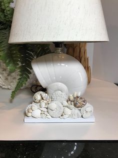 a white lamp sitting on top of a table next to a vase with flowers in it