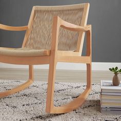 a wooden rocking chair sitting on top of a rug next to a stack of books