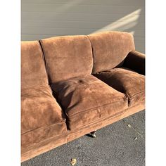 a brown couch sitting in front of a white wall with a shadow cast on it