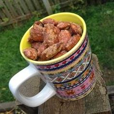 a yellow cup filled with food sitting on top of a wooden table next to a fence