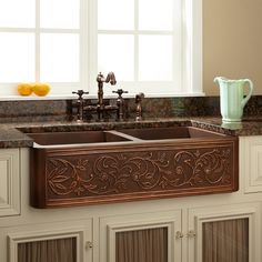 a kitchen sink with an intricate design on the front and side, along with two faucets