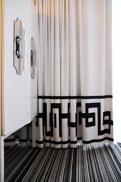 a bathroom with black and white decor on the shower curtain, toilet paper dispenser and mirror