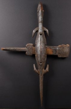 an old metal lizard mounted to the side of a wall in front of a black background