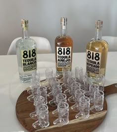 several bottles and glasses are arranged on a tray with wine glasses in front of them