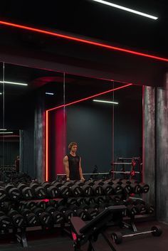 a man standing in the middle of a gym with rows of treadmills behind him