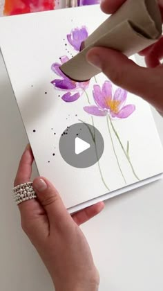 a person is painting flowers on a piece of paper