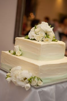 a three tiered cake with white flowers on top