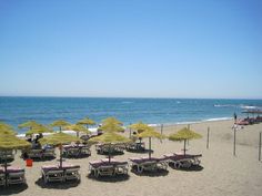 there are many umbrellas and chairs on the beach