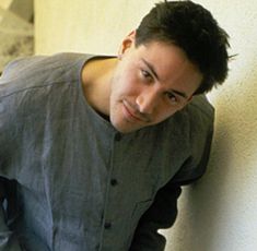 a young man leaning against a wall with his hand on the back of his head