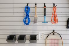 tennis rackets and other sports equipment hang on the wall