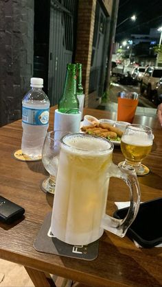 a table topped with two mugs filled with liquid and food next to a cell phone