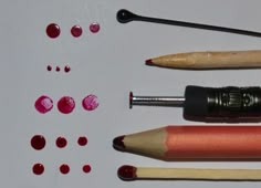 several different types of pencils and markers on a white surface with red circles around them