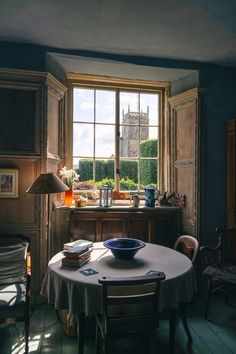 a table with a bowl on it in the middle of a room next to a window