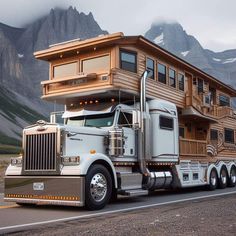 a large semi truck with a house on the back is parked in front of mountains