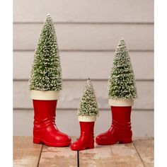 three red boots with christmas trees in them sitting on a wooden table next to each other