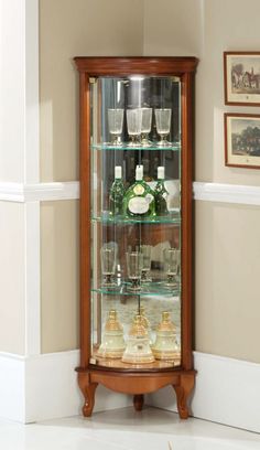 a wooden display case filled with lots of bottles and glasses on top of a white floor