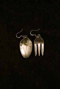 two silver spoons sitting next to each other on top of a black tablecloth