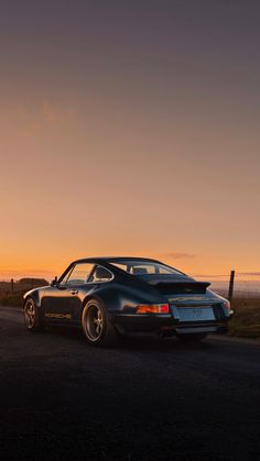 a black sports car is parked on the side of the road at sunset or dawn