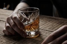 a hand holding a glass on top of a wooden table