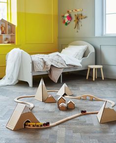 a child's bedroom with a train set and toy cars on the floor in front of it