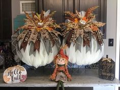 two pumpkins decorated with feathers and fall decorations