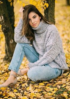 a woman sitting on the ground next to a tree