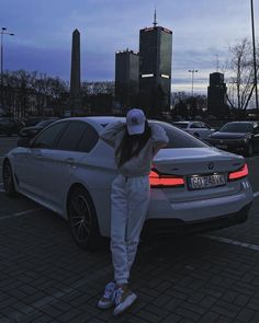 a woman standing next to a car in a parking lot with her hands on her head