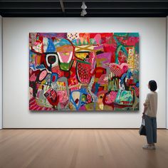 a woman standing in front of a large painting on display at an art gallery,