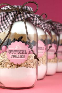 three jars filled with cookies and oatmeal sitting on top of a pink surface