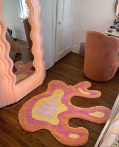 a room with a mirror, chair and rug on the floor