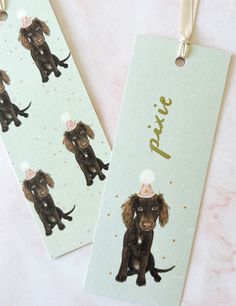 two tags with dogs wearing party hats on them, one has a name tag attached to it