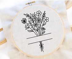 a cross stitch pattern with flowers in the center on a white cloth and a wooden hoop