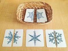 four snowflake coasters sitting on top of a table next to a wicker basket