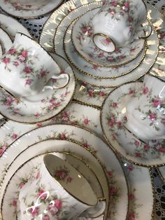 a table topped with lots of white plates and cups covered in pink flowered china