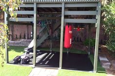 a red punching bag sitting on top of a green field next to a metal structure