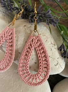 pink crochet tear earrings on top of a rock next to lavenders and flowers