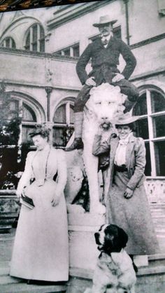 an old black and white photo of three people standing in front of a building with a horse statue