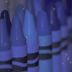 several blue and black crayons lined up in rows with sparkles on them