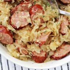 a bowl filled with sausage and sauerkraut on top of a white table cloth