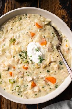 a bowl of chicken and dumpling soup with a spoon in it on a wooden table