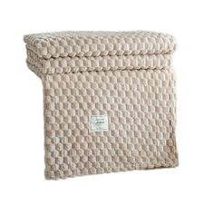 a beige blanket with a white tag on the front and back of it, sitting in front of a white background