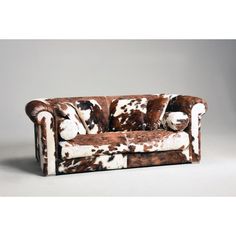 a brown and white cow print couch sitting on top of a table