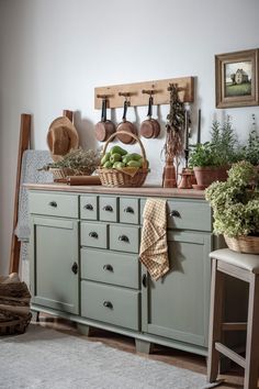 a kitchen with green cupboards and potted plants on the counter top in front of it