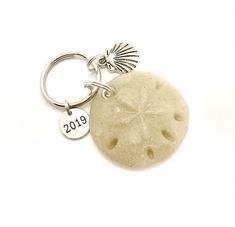 a white sand dollar keychain with the word 2013 written on it and a starfish charm