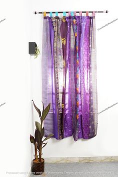 a purple curtain hanging on the wall next to a potted plant