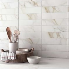 kitchen utensils in basket on counter next to white tile backsplashes