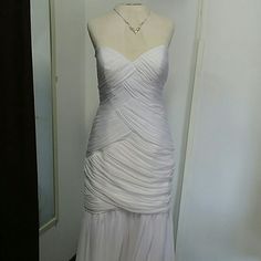 a white dress is on display in a room with a mannequin behind it