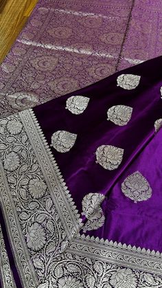 This Exclusive Mashroo Katan Silk Banarasi Saree in deep purple is a timeless masterpiece that exudes elegance and tradition. Crafted from premium quality blended Katan silk, its smooth and lustrous texture enhances its luxurious appeal. The saree is adorned with intricate silver zari weaving buttas scattered gracefully across the body, creating a delicate shimmer that beautifully contrasts the rich purple hue. The highlight of this saree lies in its wide traditional border, meticulously woven with classic motifs that reflect the grandeur of Banarasi craftsmanship. The border adds a regal touch, making it perfect for festive occasions and grand celebrations. Complementing this is the richly designed pallu, featuring elaborate patterns that showcase the finesse of traditional artistry. This Dark Purple Saree, Katan Silk Saree Banarasi, Bridal Banarasi Saree, Silk Banarasi Saree, Sarees For Girls, Silk Saree Banarasi, Purple Saree, Katan Silk, Rich Purple